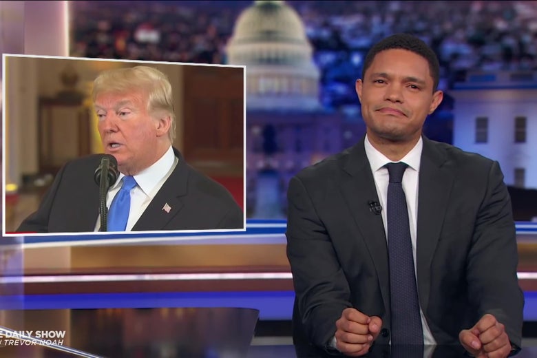 Trevor Noah in front of a photo of President Trump.